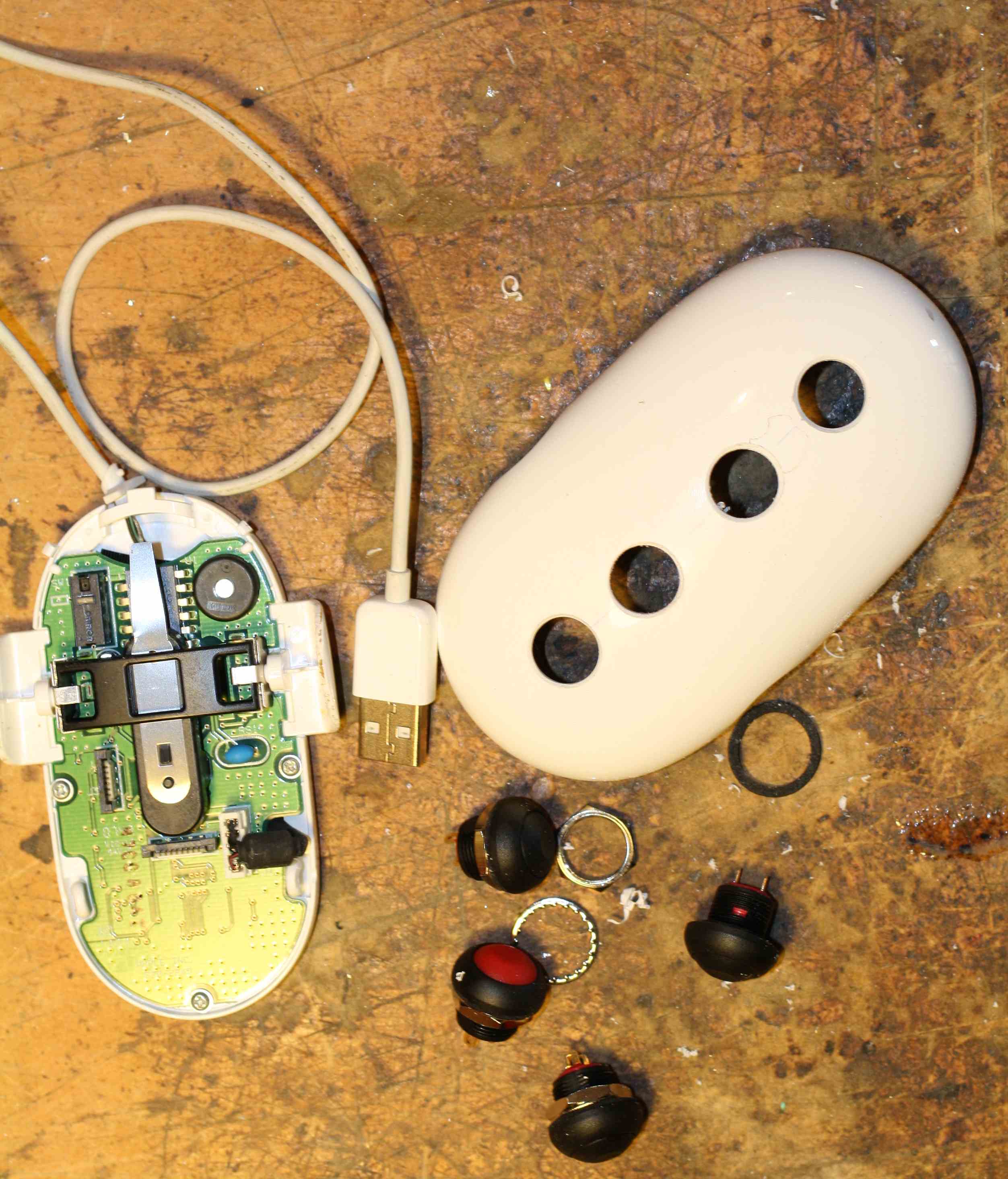 The Apple mouse disassembled with switch holes drilled in upper shell. Lower shell still has circuit board and USB cable attached (All to be removed)